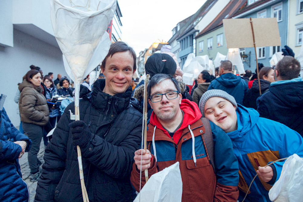 Foto zeigt drei Personen die Laternen in den Händen haben.